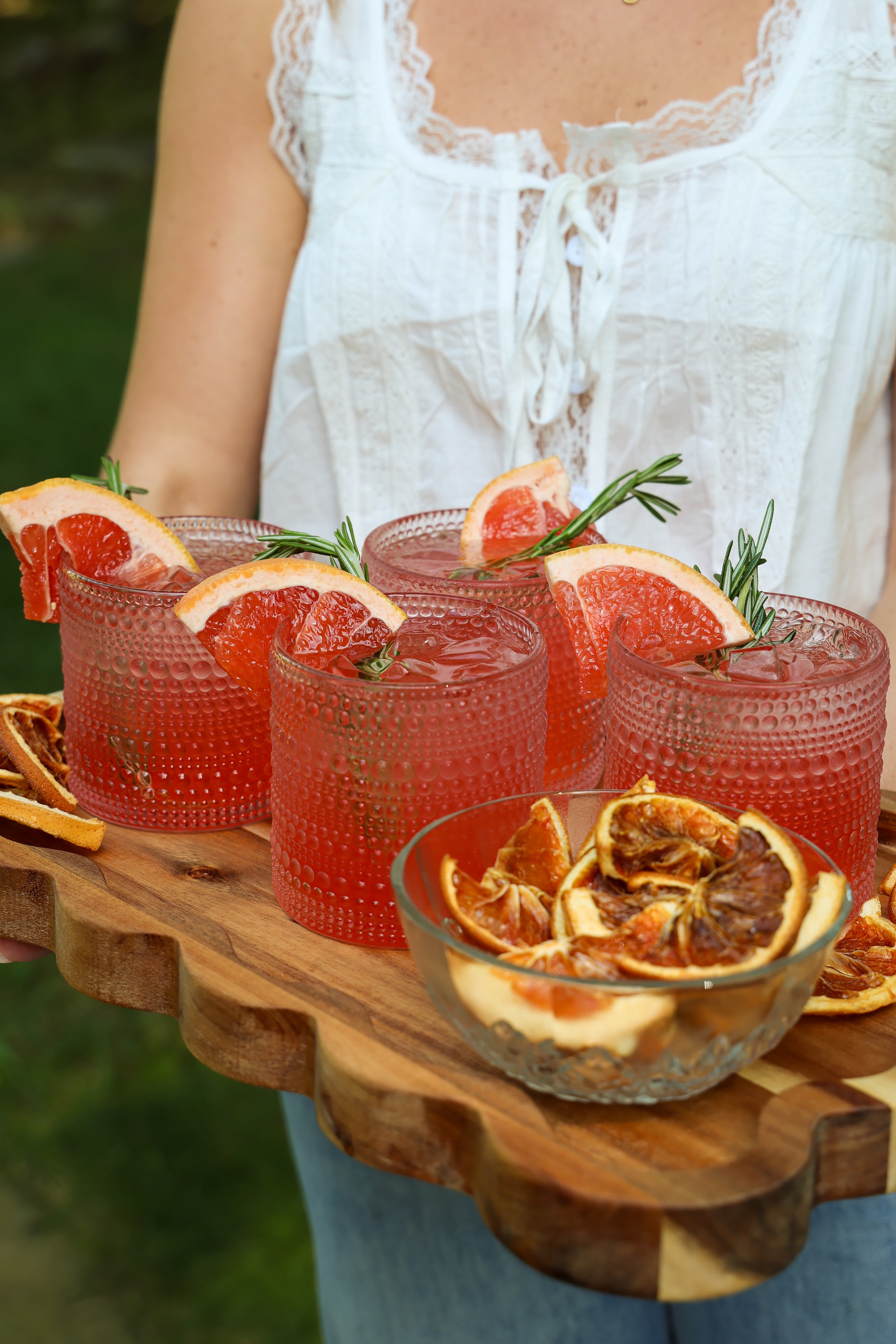 Grapefruit cocktails with rosemary garnish on wooden tray